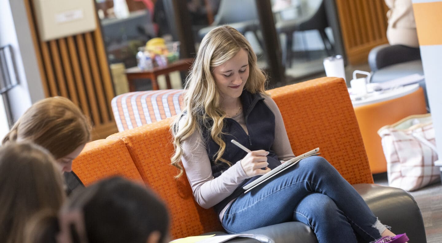 a student sits doing class work in building lobby