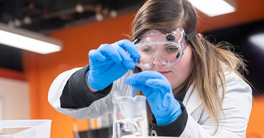 Student creating a reaction in a chemistry class.