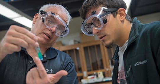 Professor showing a student a chemical reaction in a lab.
