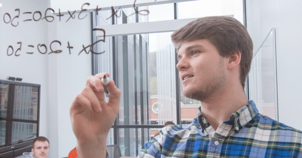 Student solves math equation in front of students.