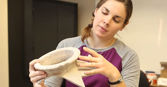 Student holding ancient pottery sherd.