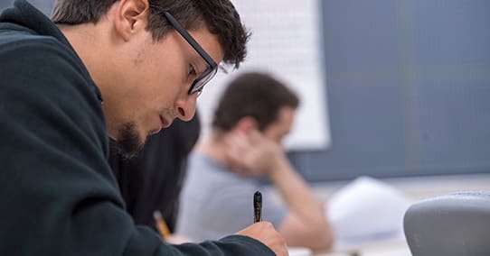 Student taking notes at his desk.