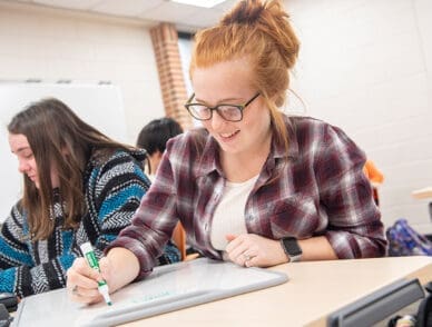 Student writing on a whiteboard in a first-year studies class.