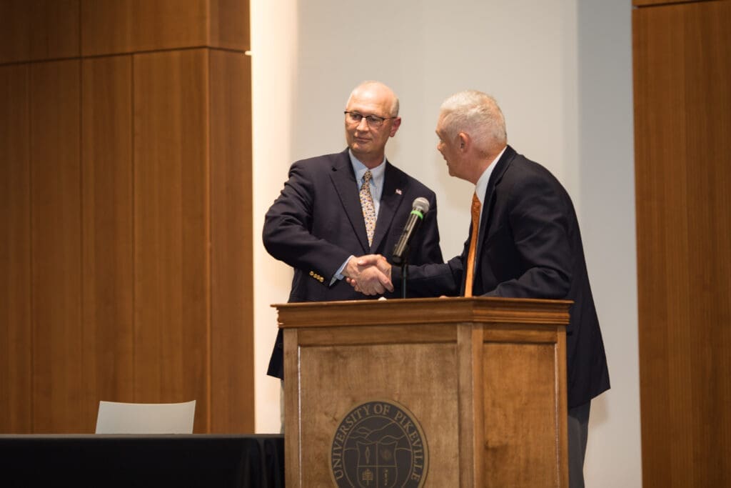 Rick Bartley and Bill Baird shaking hands as Rick is presented an award