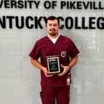 Elijah Riffe holding his plaque in front of the KYCO logo