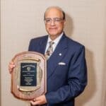 Dr. Rakesh Sachdeva holding the commemorative plaque