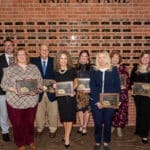 Distinguished Educators standing in front of the wall with name plaques of past inductees.